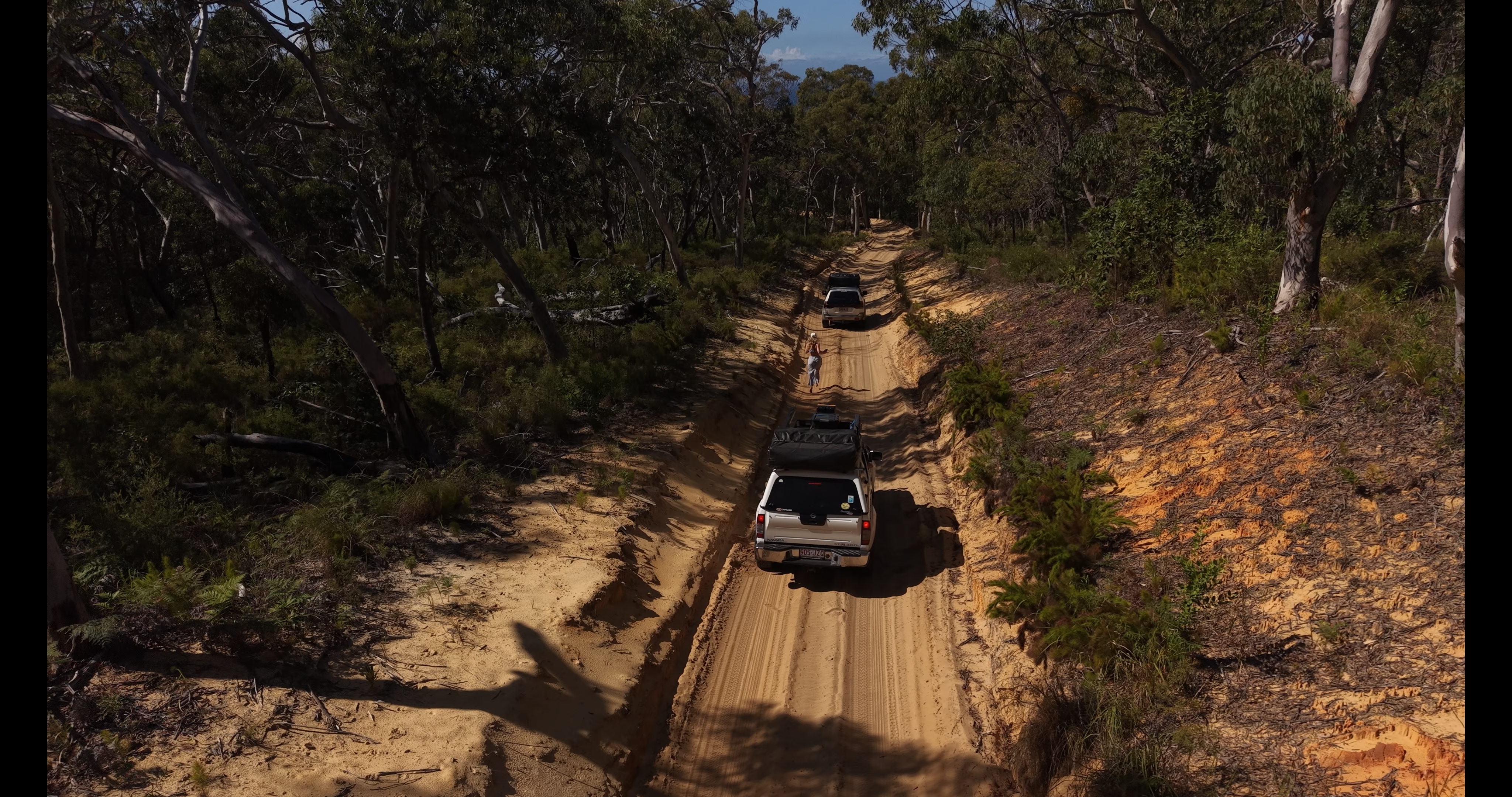 Three travellers laughing together in the back seat of a 4WD on the way to the campsite