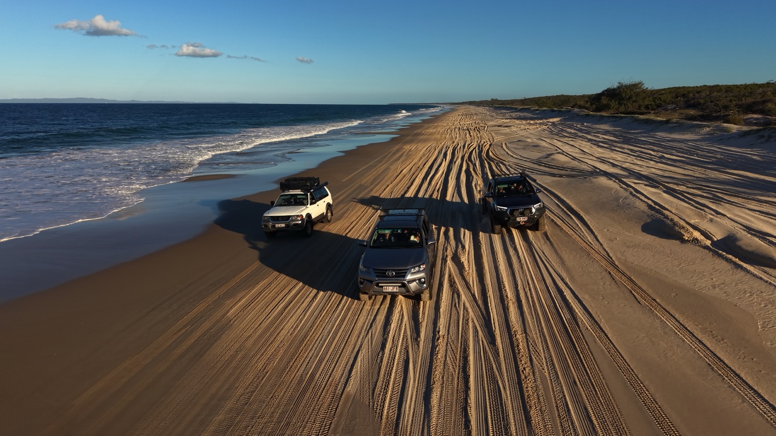 Campfire Crew four-wheel-drive convoy travelling along a Moreton Island beach