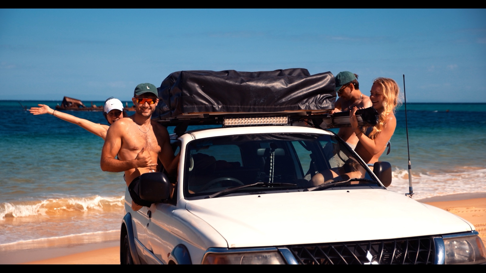 Friends gathered around a four-wheel-drive on the beach