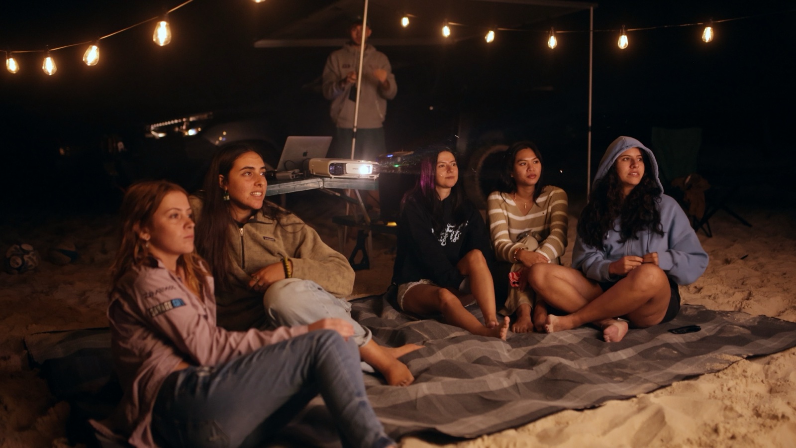 The crew watching an outdoor movie after dark